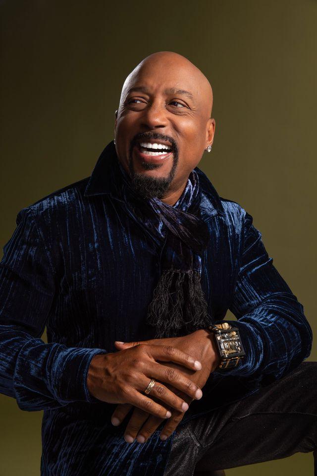 Smiling Daymond John in a royal purple velvet suit